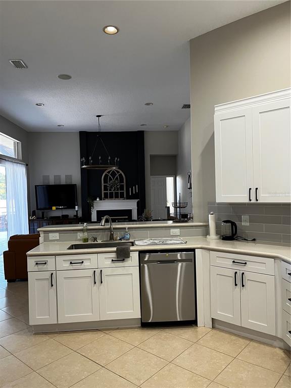 A kitchen with white cabinets, stainless steel appliances, and a view into the living room — 7742 CAMDEN HARBOUR DRIVE, BRADENTON, FL