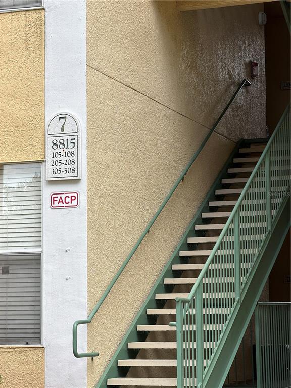 An exterior view shows a yellow stucco building with a metal staircase and unit signage — 8815 DUNES COURT UNIT 308, KISSIMMEE, FL