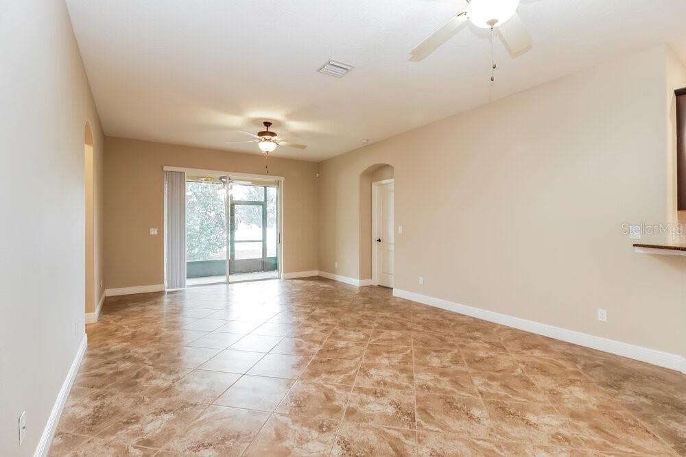 An open-concept living area features beige walls, tile flooring, and a sliding glass door — 12307 CRICKLEWOOD DRIVE, SPRING HILL, FL