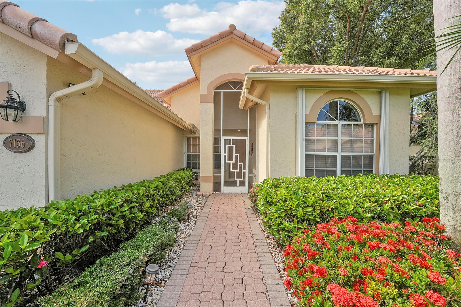 A paved walkway leads to the front entrance of a house with a tiled roof — 7136 Ashford Lane, Boynton Beach FL 33472, BOYNTON BEACH, FL
