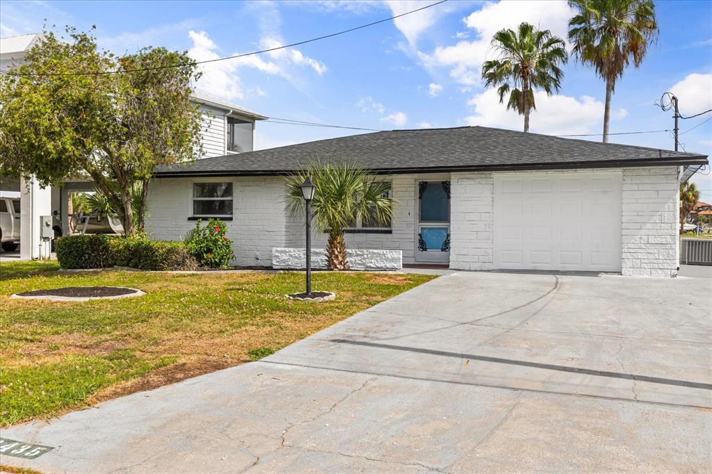 A single-story white brick house features a dark roof, a garage, and a front lawn — 3435 GULF COAST DRIVE, HERNANDO BEACH, FL
