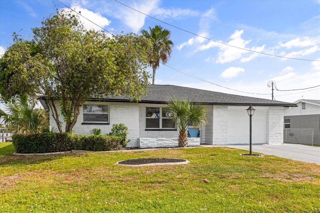 A single-story white brick house with a dark roof, a garage, and a front lawn — 3435 GULF COAST DRIVE, HERNANDO BEACH, FL