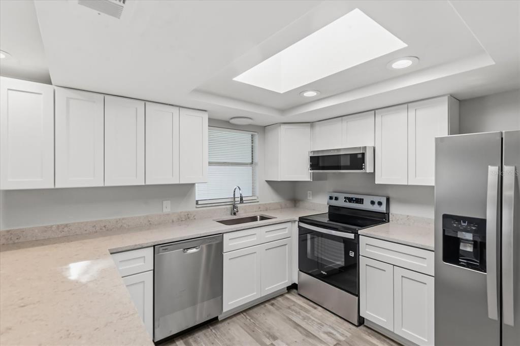 A kitchen features white cabinets, stainless steel appliances, light countertops, and a rectangular skylight — 3435 GULF COAST DRIVE, HERNANDO BEACH, FL