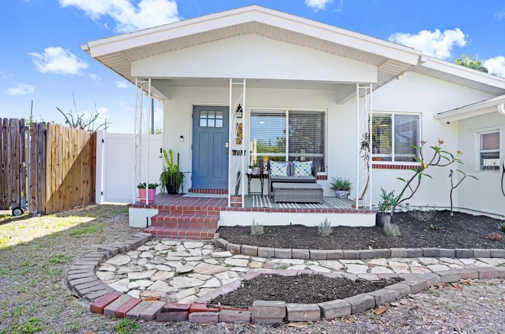 A front view of a house with a covered porch, brick steps, and stone walkway — 5347 10TH STREET N, ST PETERSBURG, FL