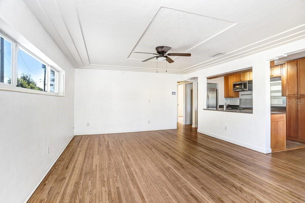 A living room with wood-look flooring, a ceiling fan, and a pass-through to the kitchen — 5347 10TH STREET N, ST PETERSBURG, FL