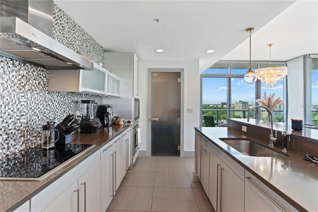 A modern kitchen features light cabinetry, a mosaic tile backsplash, and a view of trees — 260 S OSCEOLA AVENUE UNIT 1106, ORLANDO, FL