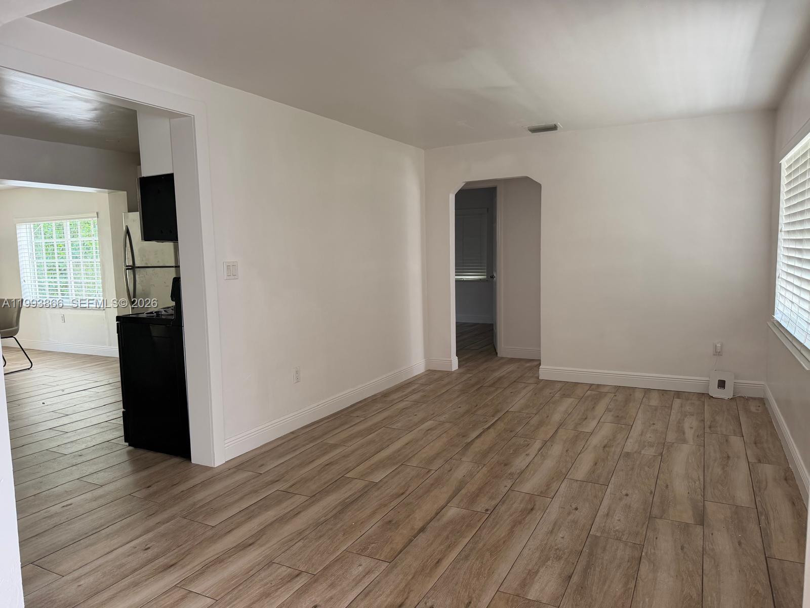 An interior view shows a living area with light wood-look flooring and an arched doorway — 3427 SW 64th Ave, Miami FL 33155, MIAMI, FL