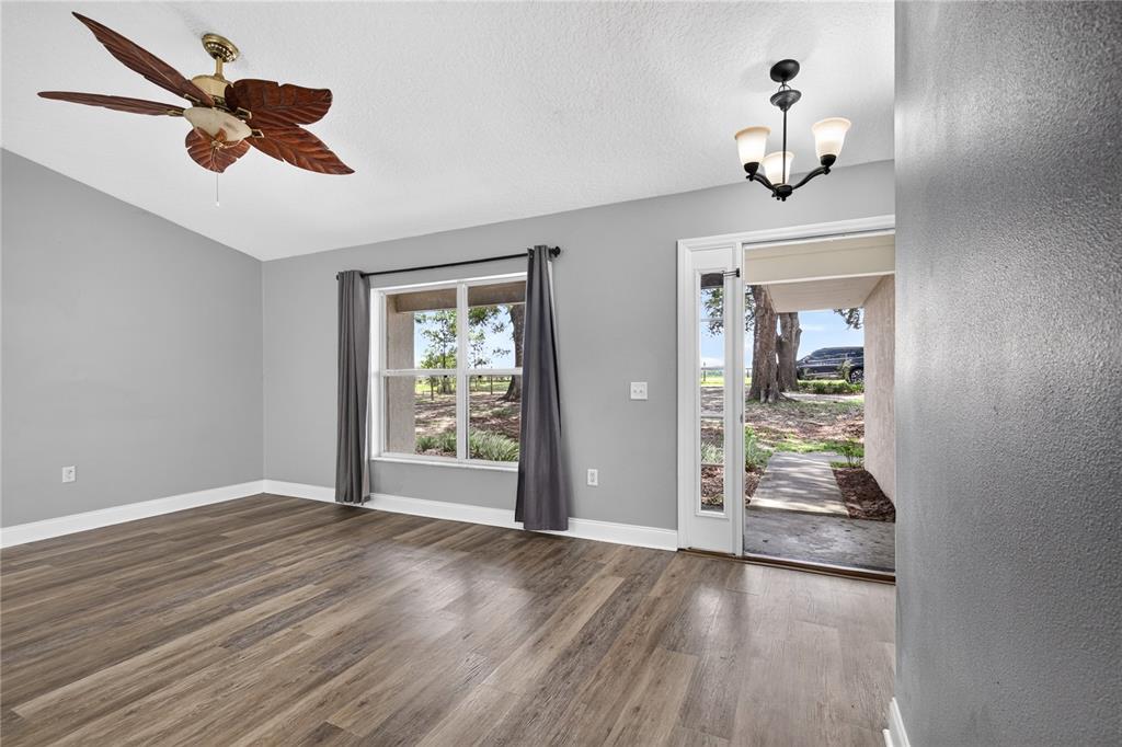 An empty room with gray walls, wood-look flooring, a ceiling fan, and an open door — 24307 ADAIR AVENUE, SORRENTO, FL