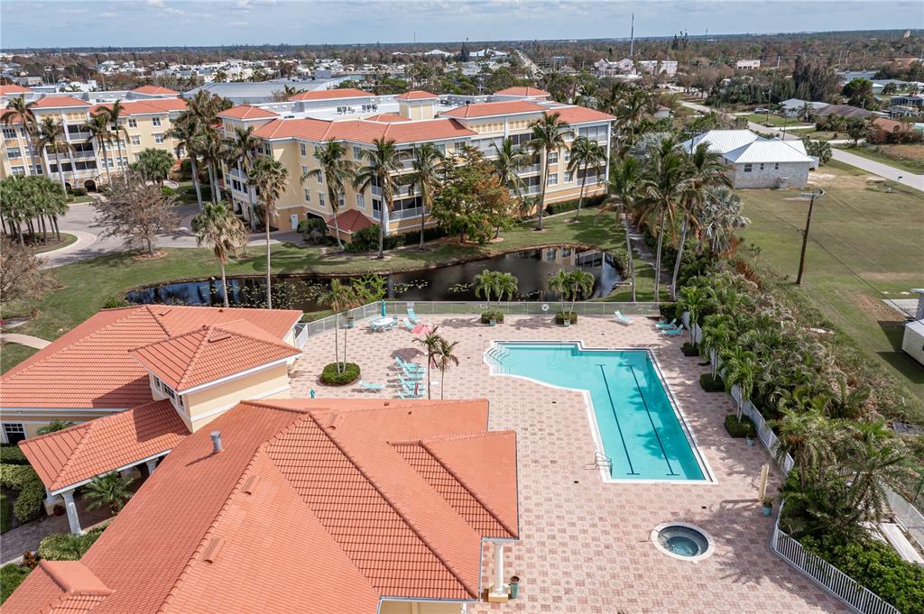 An aerial view shows a swimming pool, hot tub, and clubhouse with red tile roofs — 255 WEST END DRIVE UNIT 4205, PUNTA GORDA, FL