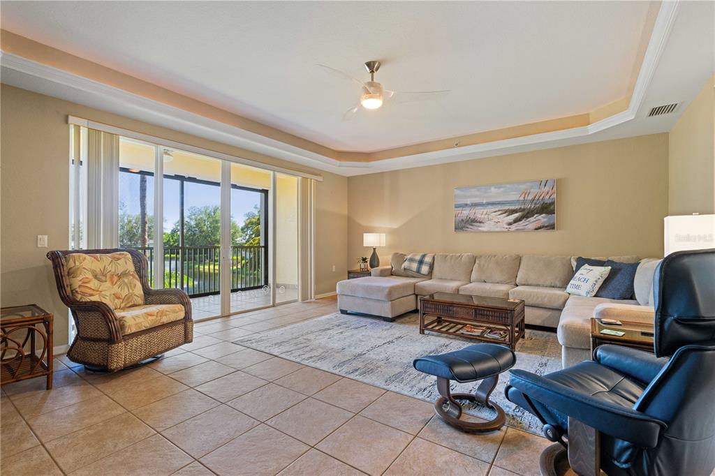 A living room features tile floors, a sectional sofa, a wicker chair, and a balcony view — 255 WEST END DRIVE UNIT 4205, PUNTA GORDA, FL