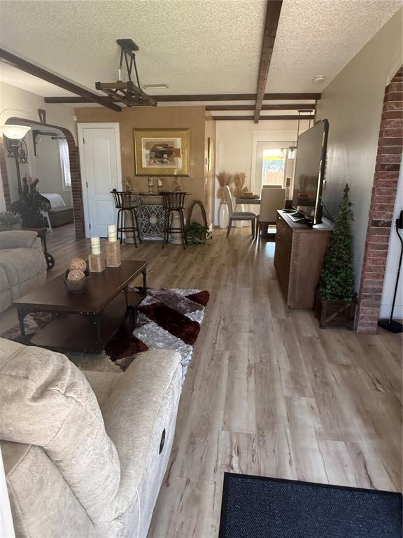 A living room features wood-look flooring, exposed ceiling beams, and an arched brick entryway — 2710 CHARING CROSS WAY, ORLANDO, FL