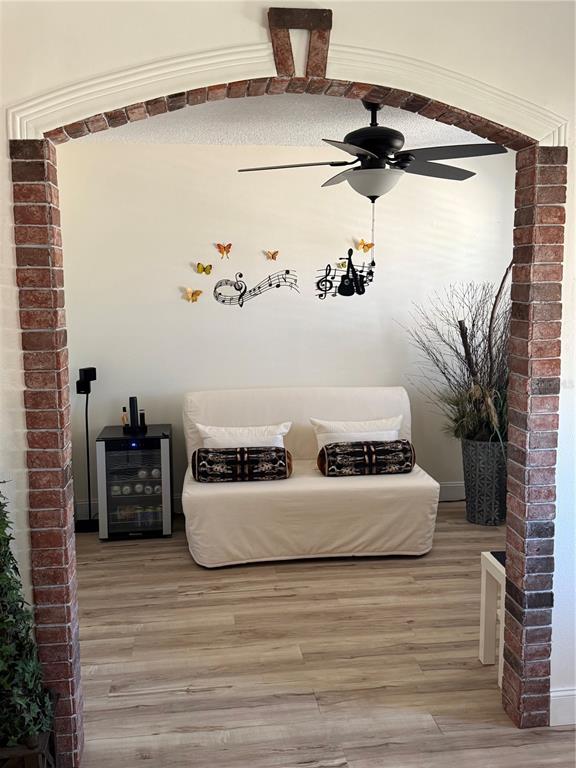 A room with a brick archway, light wood flooring, a white sofa, and wall decor — 2710 CHARING CROSS WAY, ORLANDO, FL