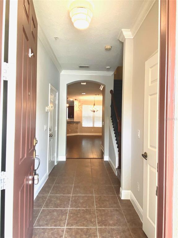 A tiled entryway leads to an arched doorway opening into a living area with stairs — 4956 LUGE LANE, ORLANDO, FL