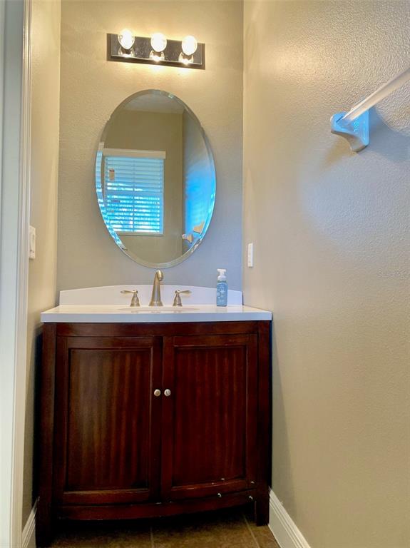 A bathroom features a dark wood vanity, white countertop, oval mirror, and three-light fixture — 4956 LUGE LANE, ORLANDO, FL