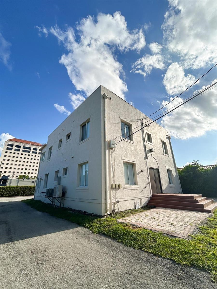 A two-story, light-colored stucco building with a paved entrance and a nearby high-rise structure — 29 Oviedo Ave, Coral Gables FL 33134, CORAL GABLES, FL