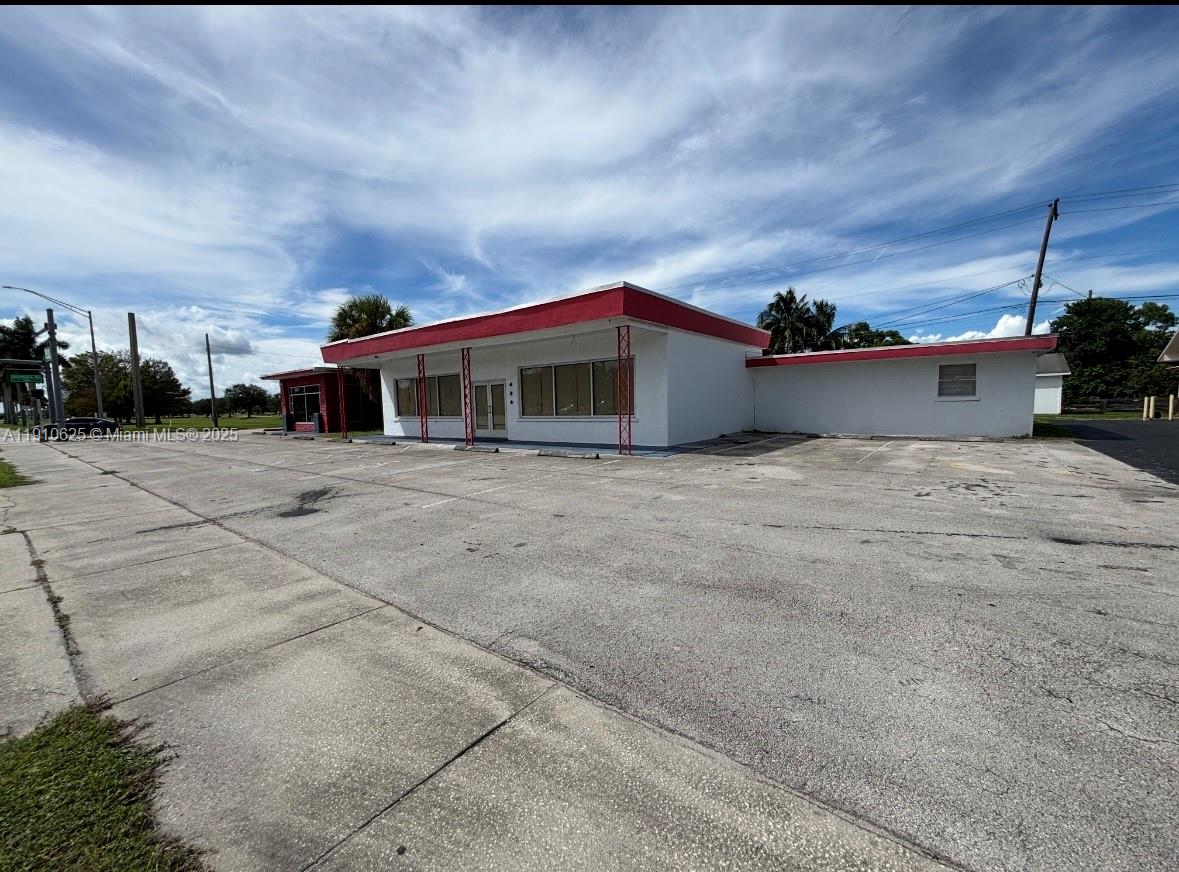 A single-story commercial building with a flat roof and a large paved parking lot — 441 W Sugarland Hwy, Clewiston FL 33440, CLEWISTON, FL