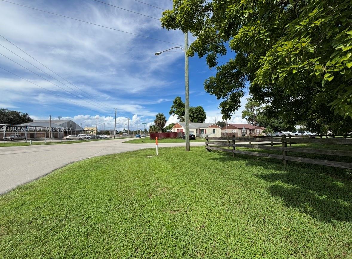 A grassy lot with a wooden fence sits beside a road near suburban houses — 441 W Sugarland Hwy, Clewiston FL 33440, CLEWISTON, FL
