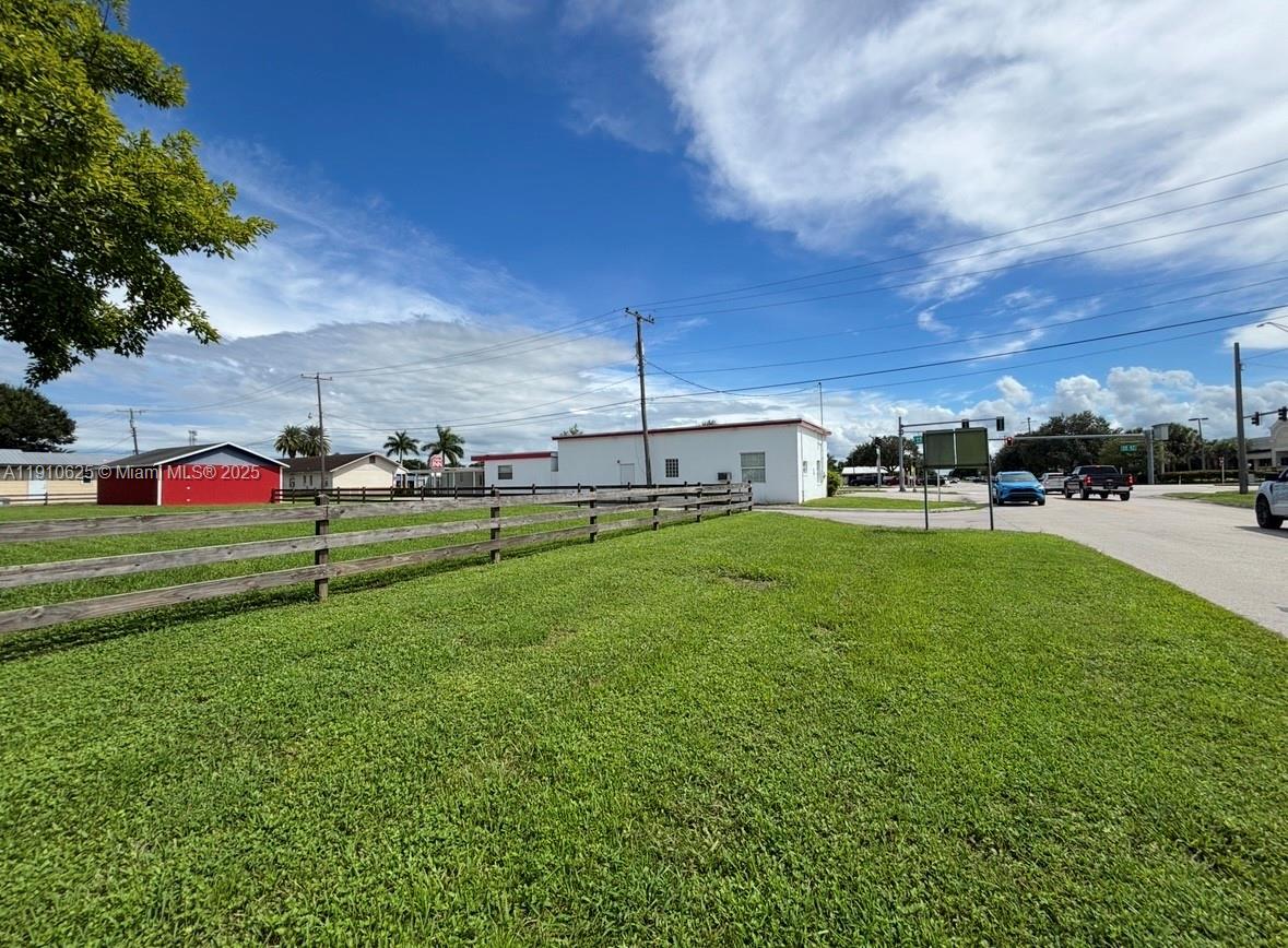 A grassy lot with a wooden fence and a white building under a blue sky — 441 W Sugarland Hwy, Clewiston FL 33440, CLEWISTON, FL