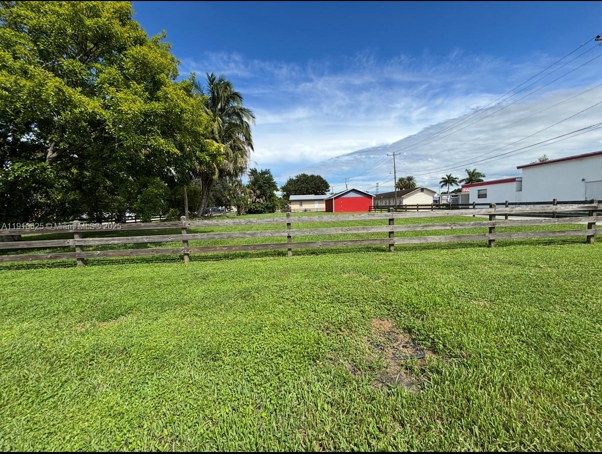 A grassy lot features a wooden split-rail fence under a blue sky with clouds — 441 W Sugarland Hwy, Clewiston FL 33440, CLEWISTON, FL