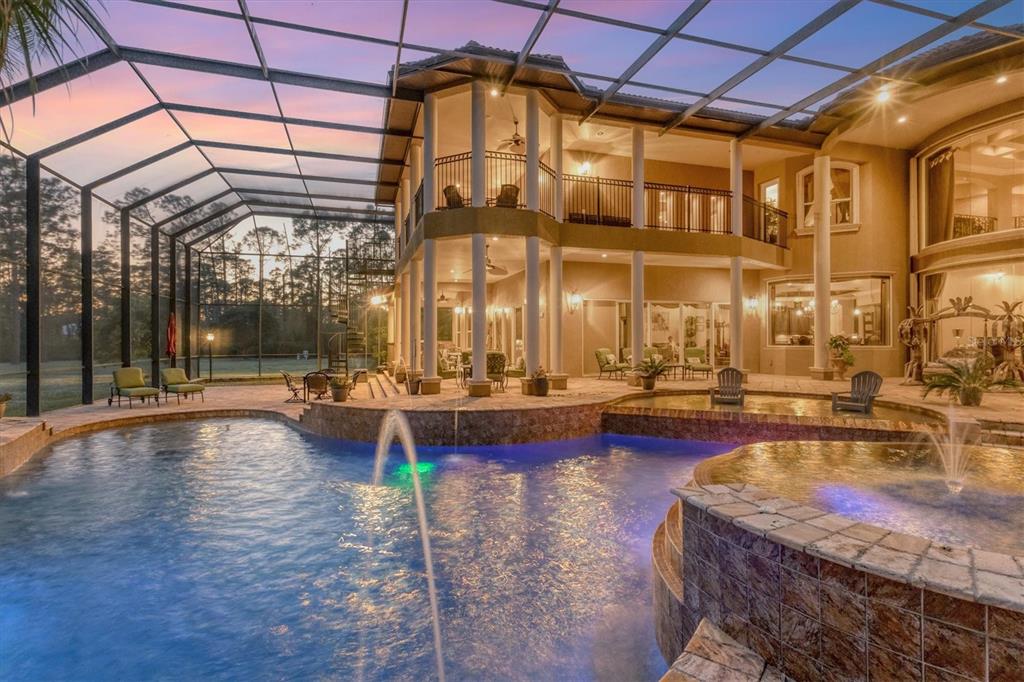 A two-story house with a screened-in pool, spa, and patio area at sunset — 3657 TROPICAIRE BOULEVARD, NORTH PORT, FL