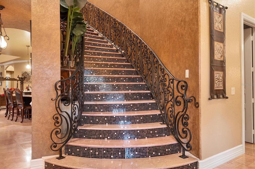 A curved staircase features stone steps with mosaic tile risers and ornate black iron railings — 3657 TROPICAIRE BOULEVARD, NORTH PORT, FL