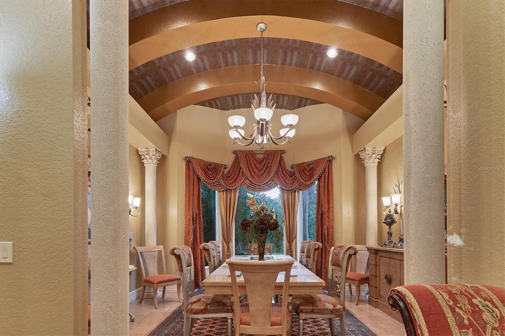 A formal dining room features a barrel-vaulted ceiling, decorative columns, and a large window treatment — 3657 TROPICAIRE BOULEVARD, NORTH PORT, FL