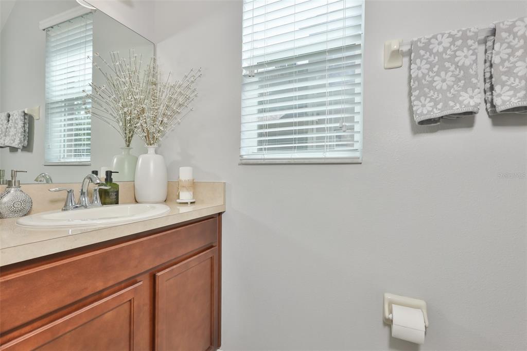A bathroom features a wooden vanity with a white sink, a mirror, and floral towels — 6370 TORRINGTON CIRCLE, LAKELAND, FL