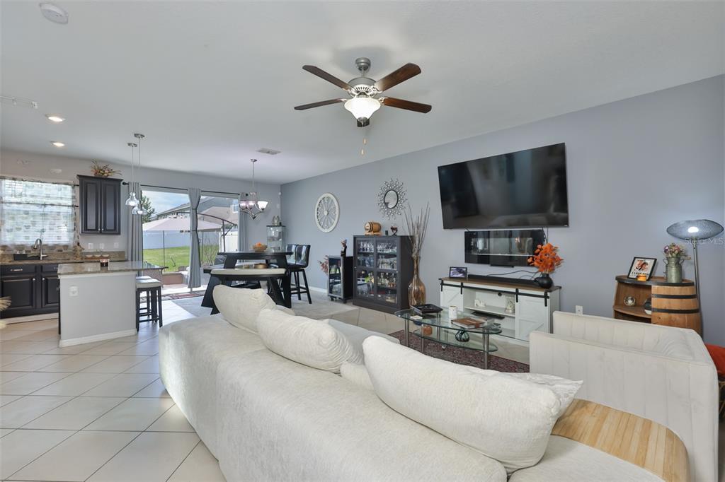 A living room with a white sofa, a wall-mounted television, and an open-concept kitchen — 6370 TORRINGTON CIRCLE, LAKELAND, FL