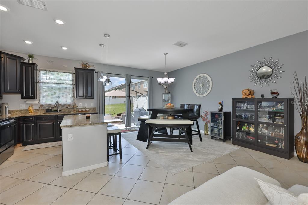 A kitchen and dining area feature dark wood cabinets, granite countertops, and tile flooring — 6370 TORRINGTON CIRCLE, LAKELAND, FL