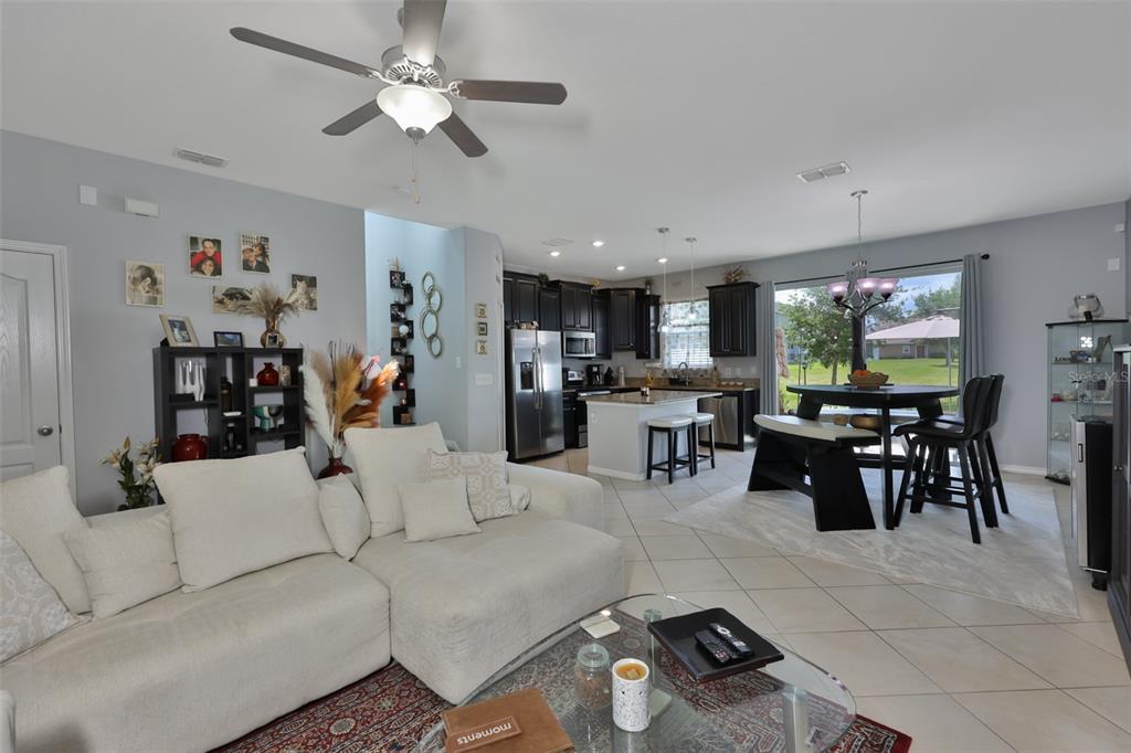 An open-concept living room and kitchen featuring tile flooring, a ceiling fan, and dark cabinetry — 6370 TORRINGTON CIRCLE, LAKELAND, FL