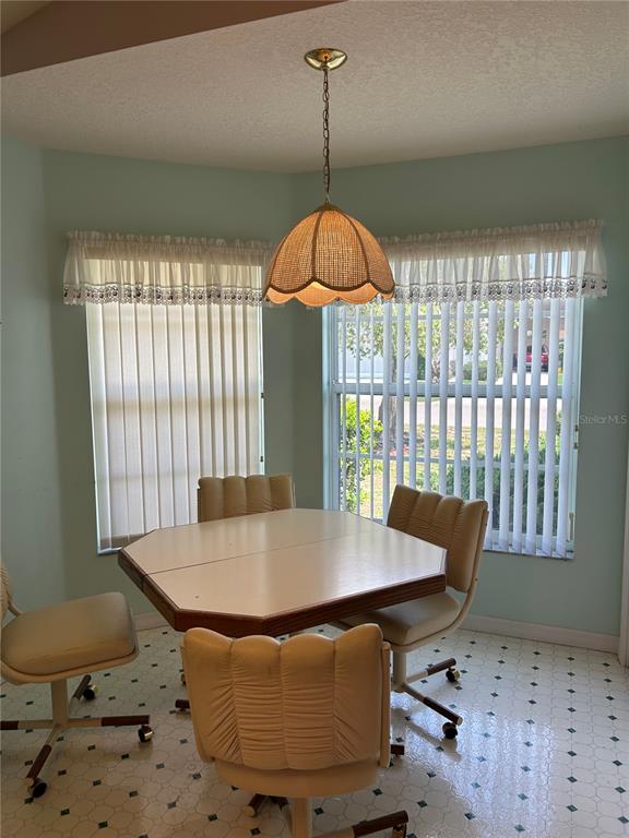 A breakfast nook features a light-colored table, four rolling chairs, and a wicker pendant light — 1030 CHALLENGER AVENUE, DAVENPORT, FL