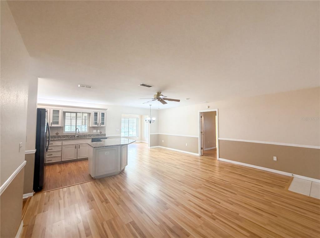 An open-concept kitchen and living area features light wood flooring, white cabinetry, and beige walls — 13763 SW 112TH TERRACE, DUNNELLON, FL
