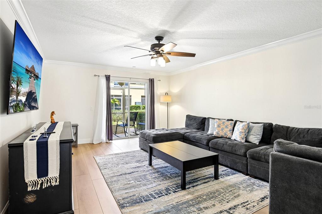 A living room features a dark sectional sofa, a coffee table, and a wall-mounted television — 3853 ISLAND WAY, ST PETERSBURG, FL