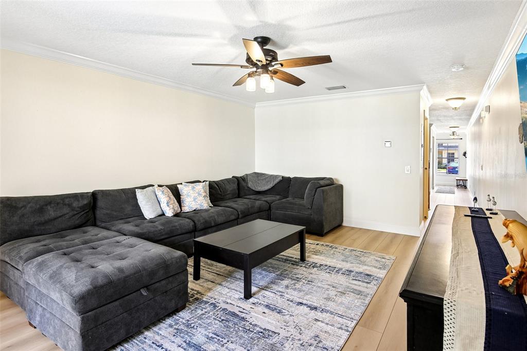 A living room features a large gray sectional sofa, a coffee table, and a ceiling fan — 3853 ISLAND WAY, ST PETERSBURG, FL