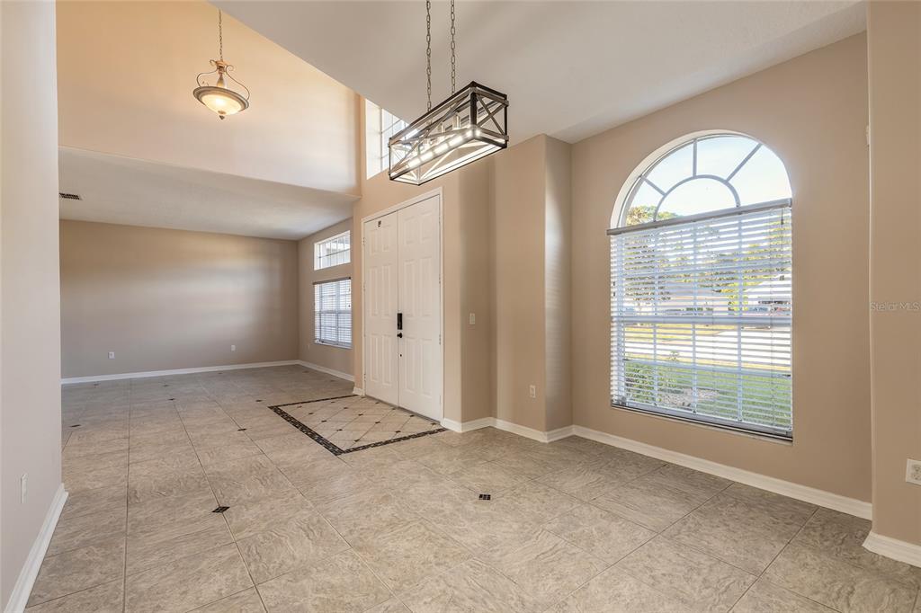 An entryway with high ceilings, tile flooring, a chandelier, and a large arched window — 1424 NEW BOLTON DRIVE, PORT ORANGE, FL