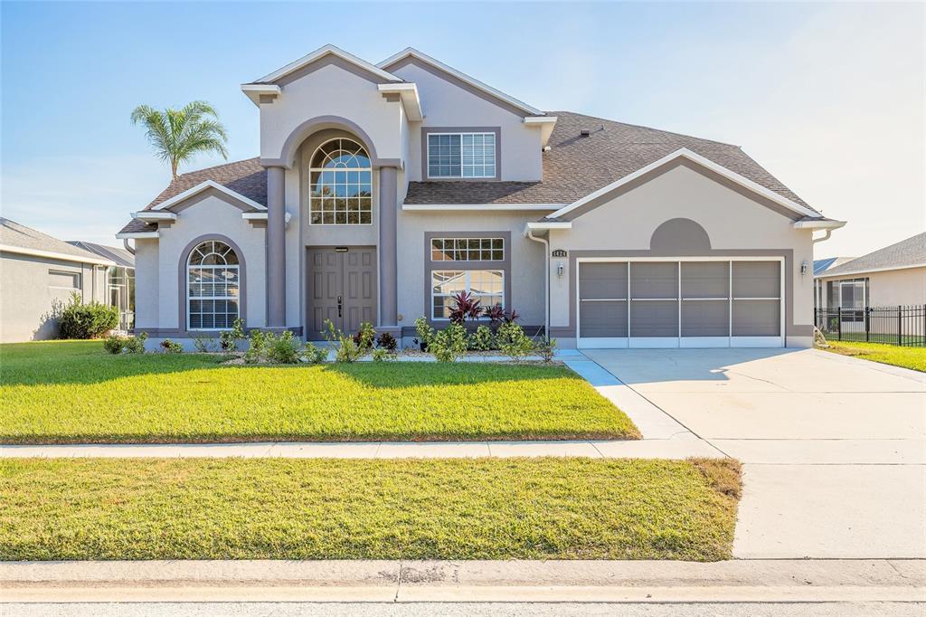 A two-story suburban house with a gray stucco exterior, arched entryway, and attached garage — 1424 NEW BOLTON DRIVE, PORT ORANGE, FL