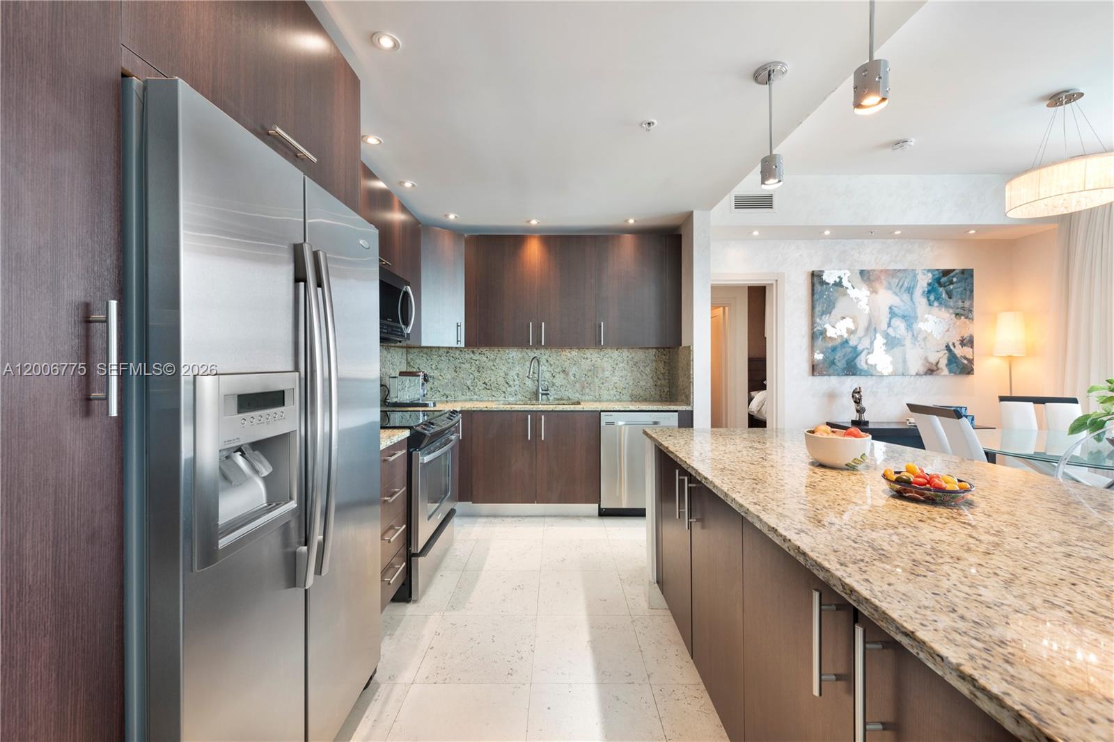 A modern kitchen features dark wood cabinets, granite countertops, stainless steel appliances, and tile flooring — 1945 S Ocean Dr # 1812, Hallandale Beach FL 33009, HALLANDALE BEACH, FL