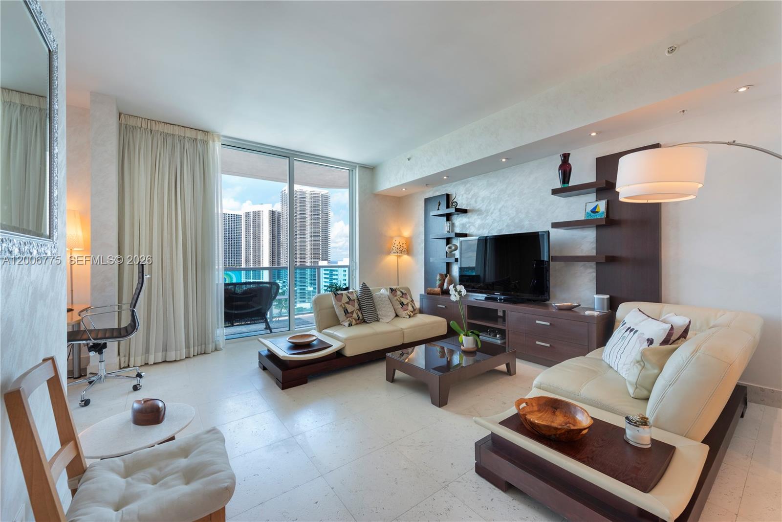 A modern living room features cream leather sofas, a dark wood entertainment unit, and floor-to-ceiling windows — 1945 S Ocean Dr # 1812, Hallandale Beach FL 33009, HALLANDALE BEACH, FL