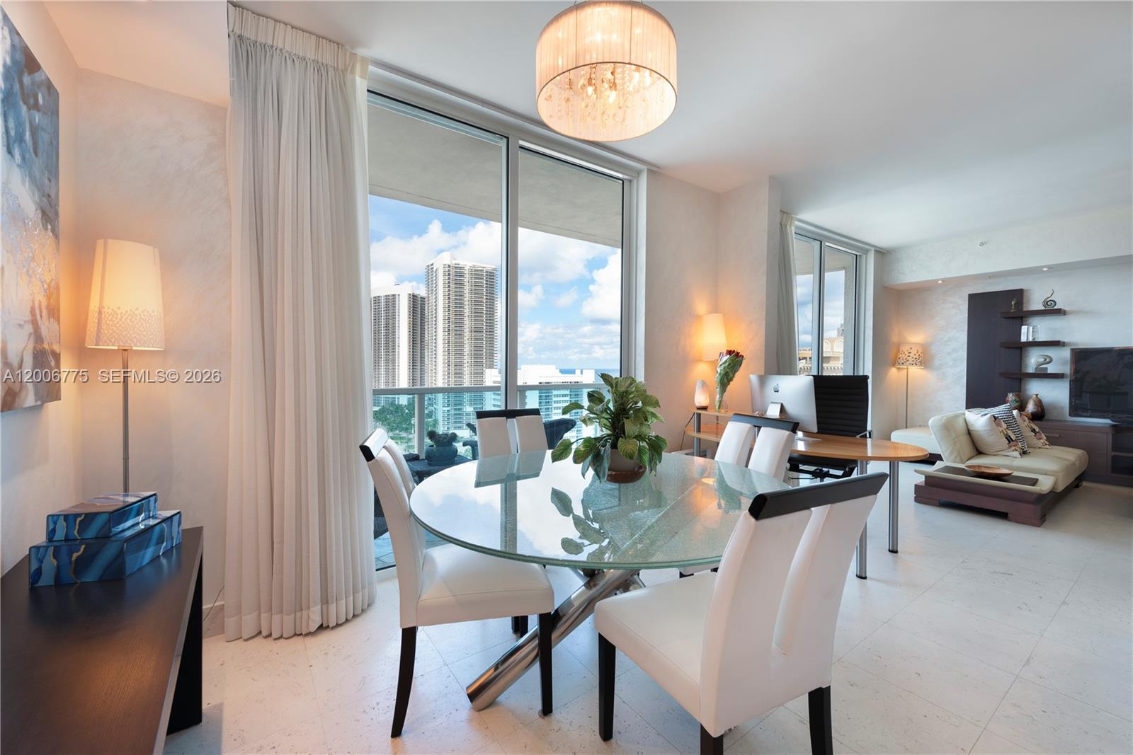 A dining area with a glass table and white chairs features floor-to-ceiling windows overlooking buildings — 1945 S Ocean Dr # 1812, Hallandale Beach FL 33009, HALLANDALE BEACH, FL