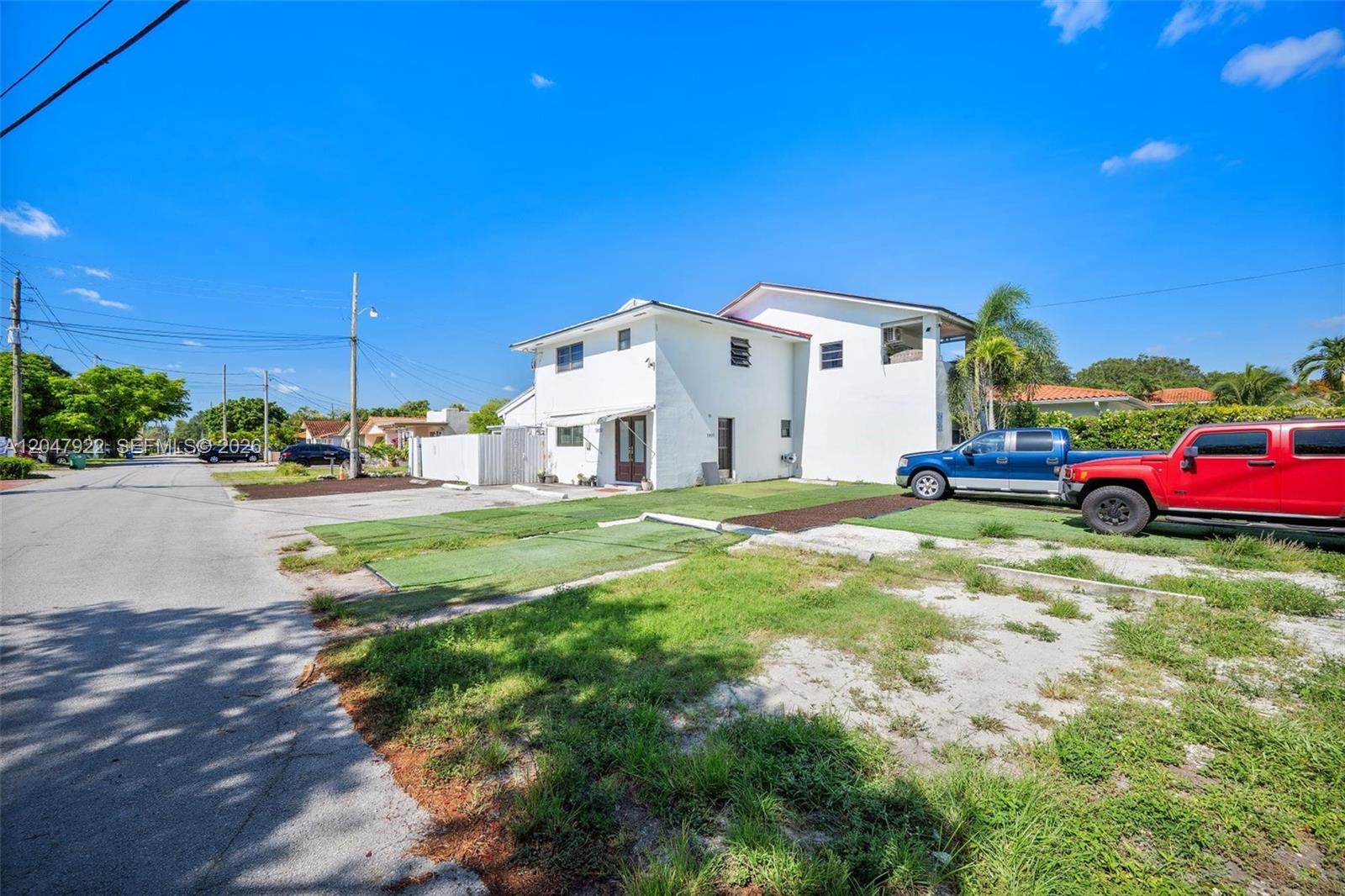 A two-story white house sits behind a dirt and grass yard with two parked trucks — 5800 SW 20th St, Miami FL 33155, MIAMI, FL