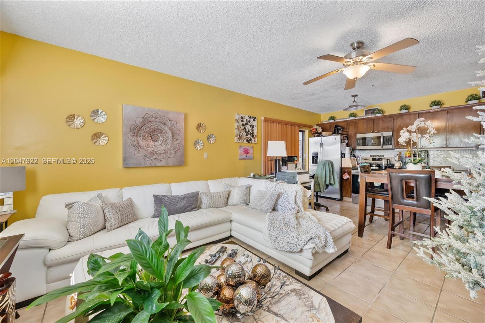 A living room with a white sectional sofa, yellow walls, and an open-concept kitchen — 5800 SW 20th St, Miami FL 33155, MIAMI, FL