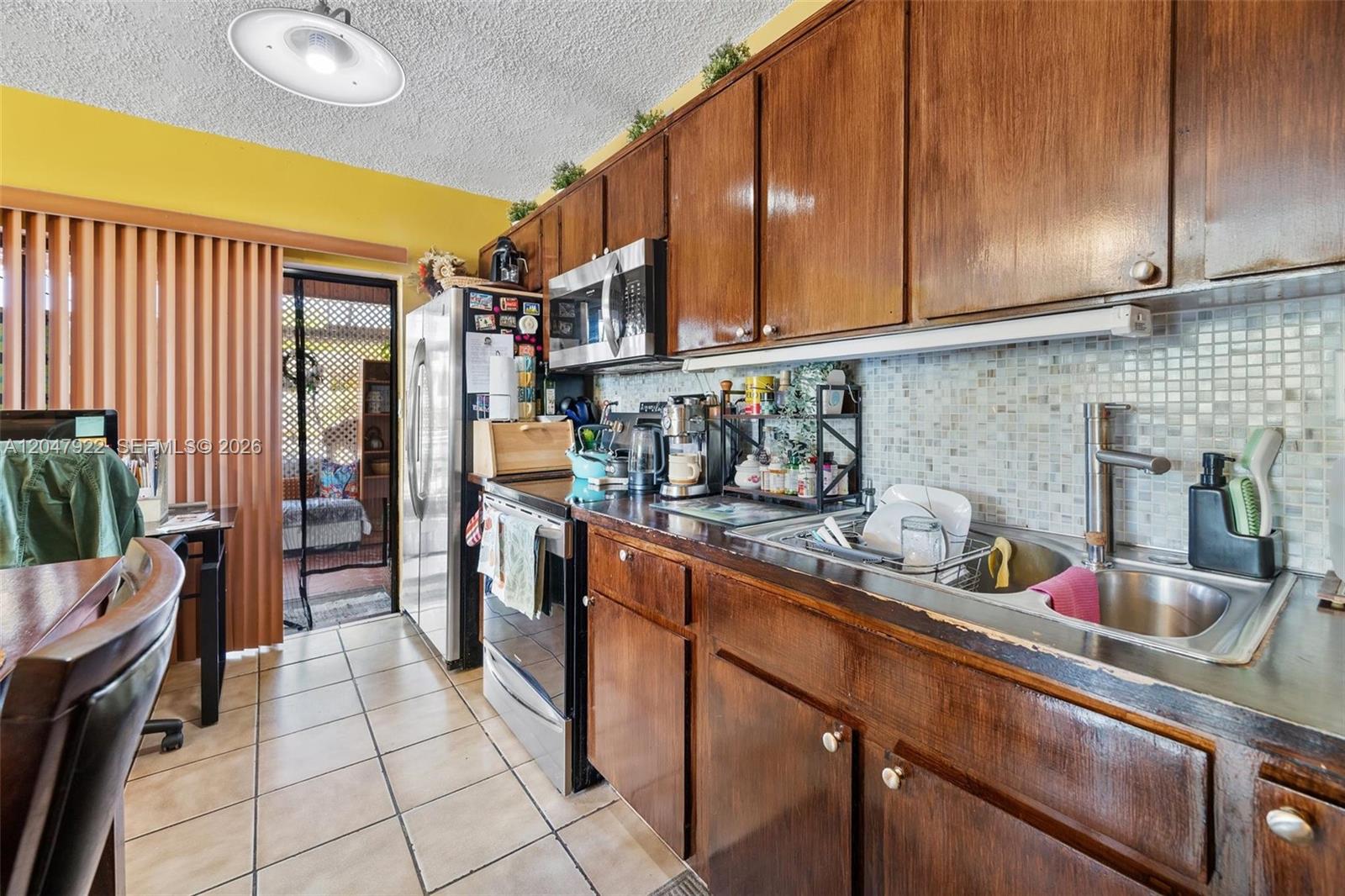 A kitchen features dark wood cabinets, stainless steel appliances, and a tiled backsplash — 5800 SW 20th St, Miami FL 33155, MIAMI, FL