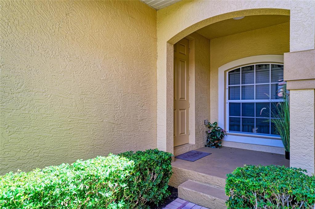 A beige stucco house exterior features a recessed entryway with a single door and window — 8261 MIRAMAR WAY UNIT 202, LAKEWOOD RANCH, FL