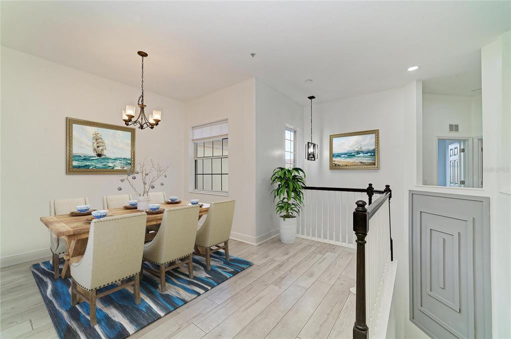 A dining area with a wooden table, upholstered chairs, and a blue patterned area rug — 8261 MIRAMAR WAY UNIT 202, LAKEWOOD RANCH, FL