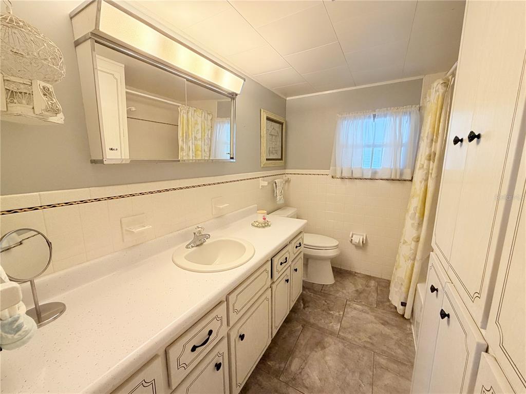 A bathroom features a white vanity, a large mirror, a toilet, and a shower curtain — 2331 BELLEAIR ROAD UNIT 529, CLEARWATER, FL