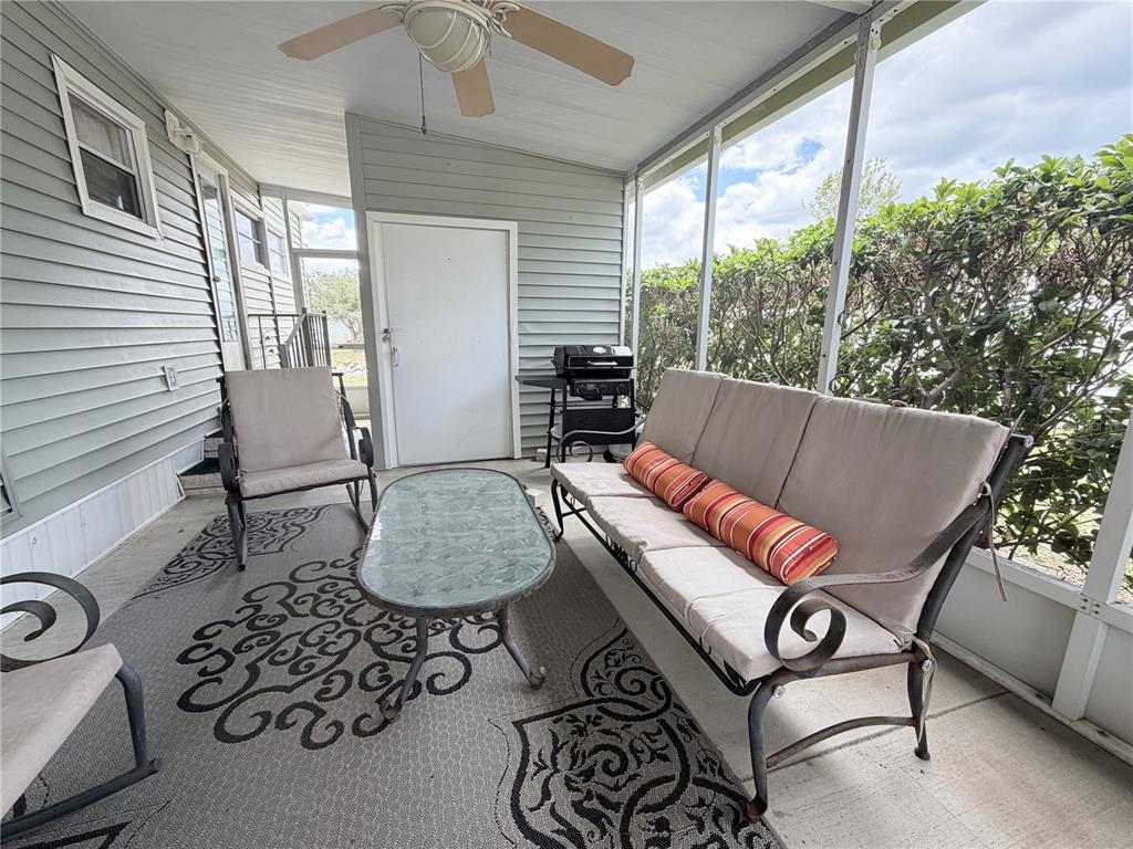 A screened-in porch features a sofa, chairs, a glass coffee table, and a ceiling fan — 2331 BELLEAIR ROAD UNIT 529, CLEARWATER, FL