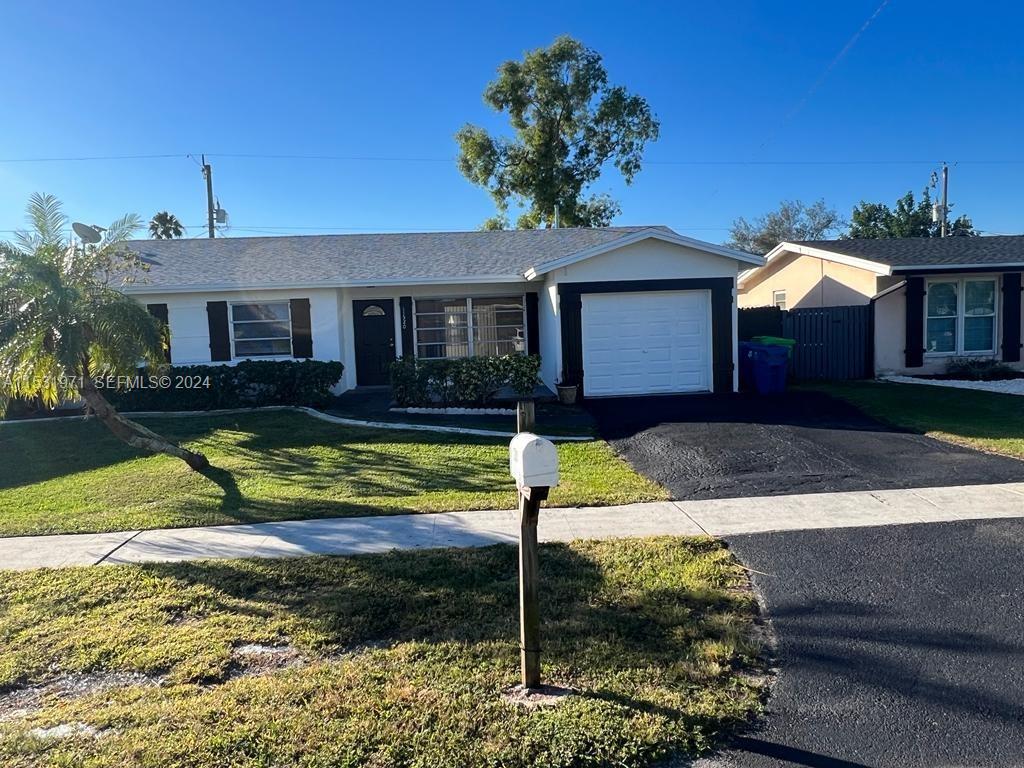A single-story house with a white exterior, black trim, a garage, and a front lawn — 11520 NW 31st Pl, Sunrise FL 33323, SUNRISE, FL
