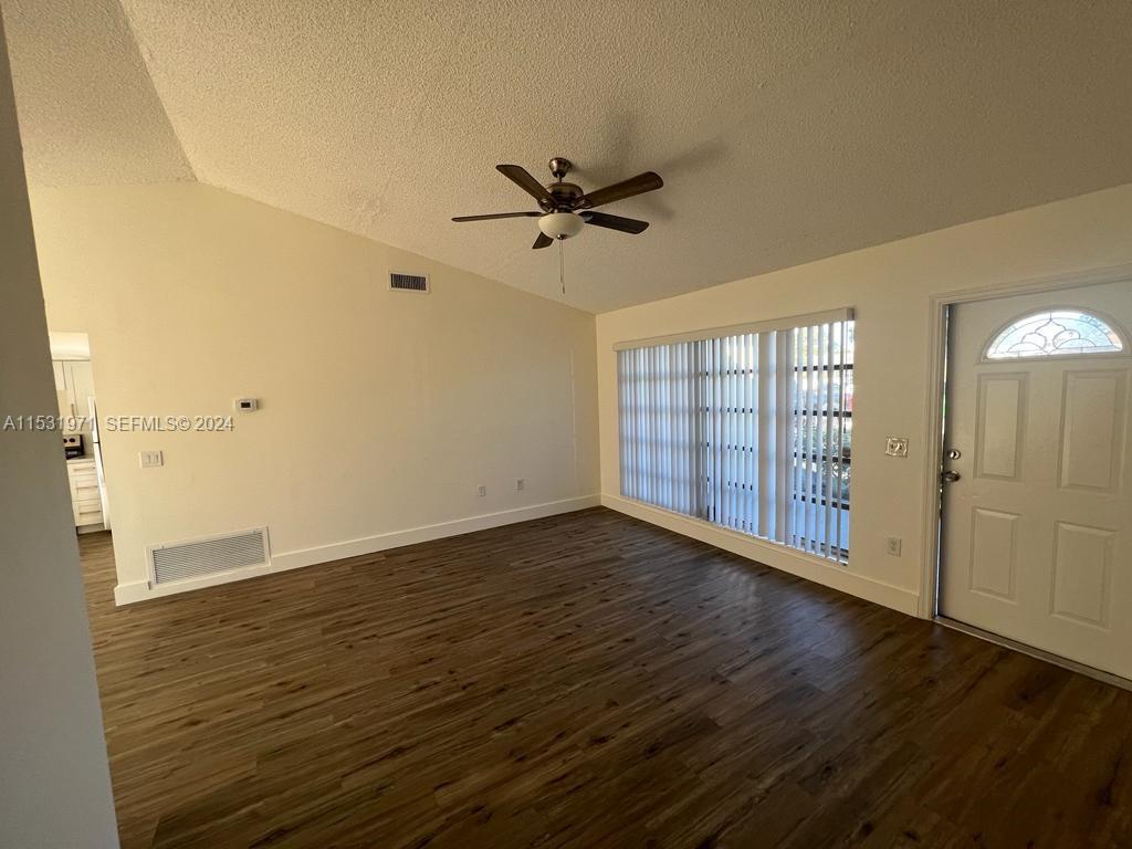 A living room features wood-look flooring, a vaulted ceiling with a fan, and vertical blinds — 11520 NW 31st Pl, Sunrise FL 33323, SUNRISE, FL