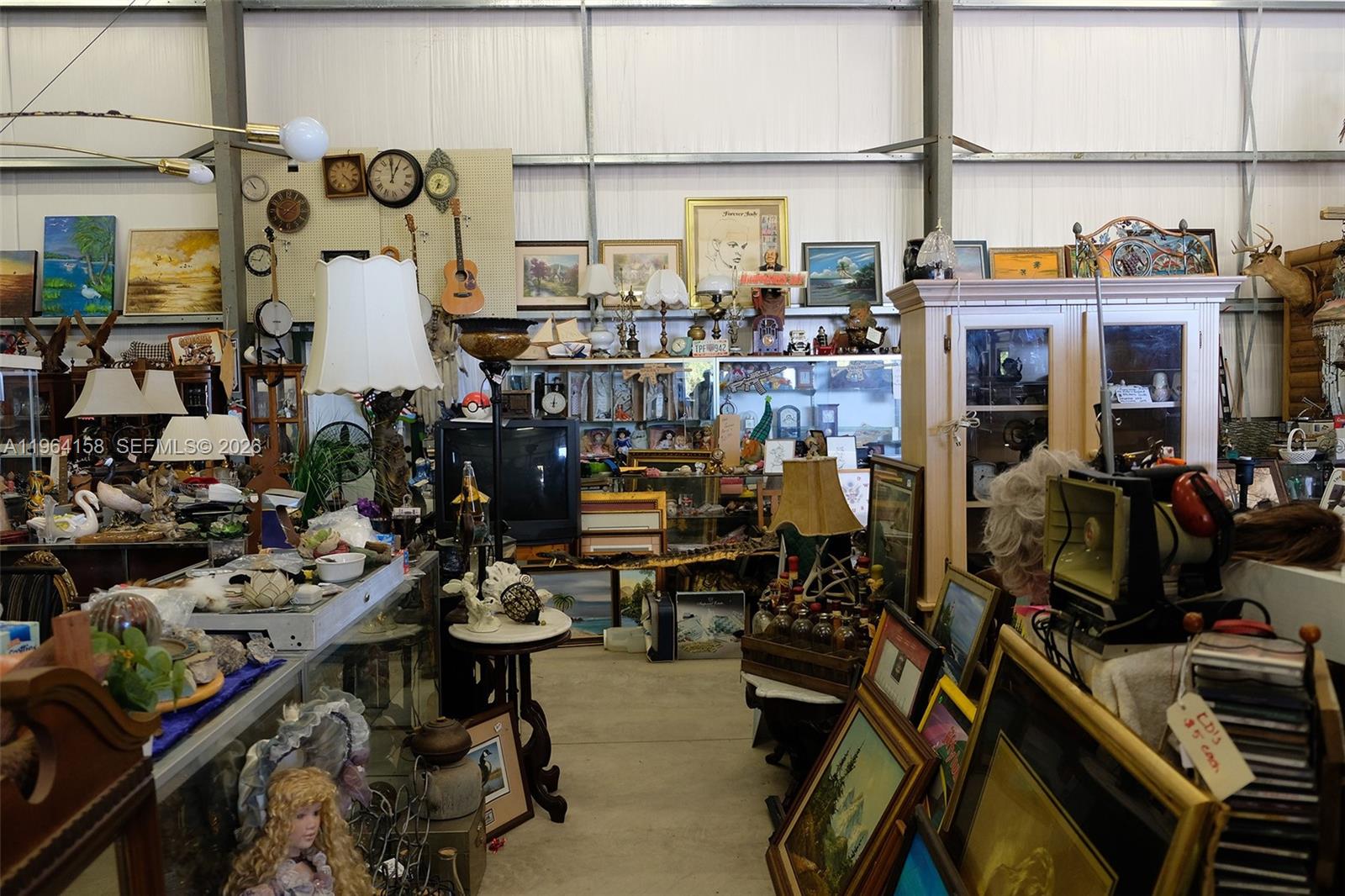 This cluttered indoor space is filled with various antiques, artwork, lamps, and decorative items — 5271 US HWY 441 SE, Okeechobee FL 34974, OKEECHOBEE, FL