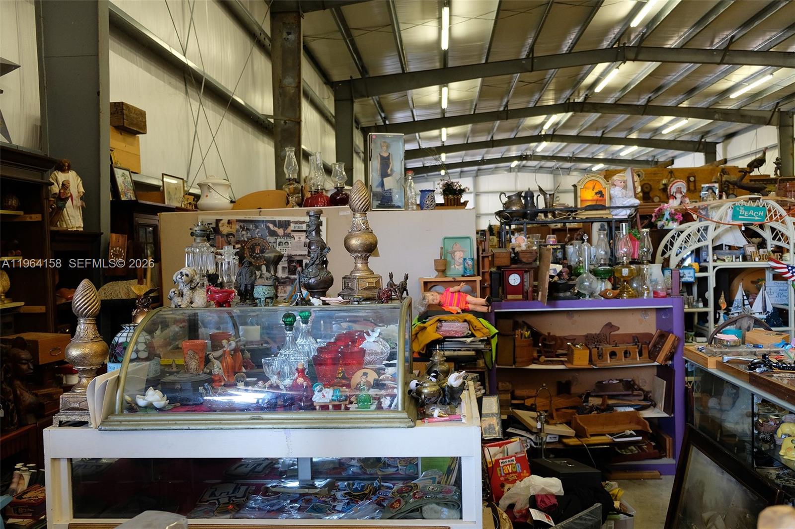 An indoor view of a cluttered antique shop filled with various collectibles, glassware, and furniture — 5271 US HWY 441 SE, Okeechobee FL 34974, OKEECHOBEE, FL
